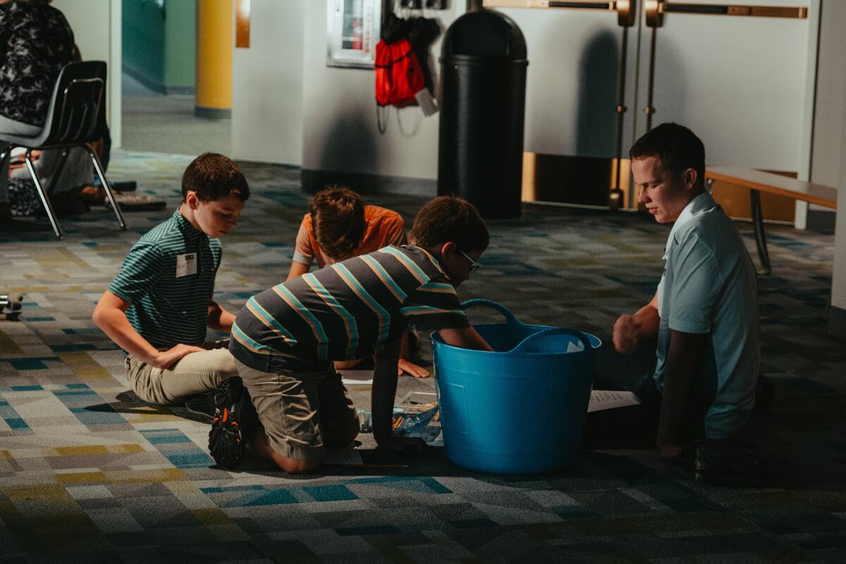 Children and a leader around an activity on the floor.
