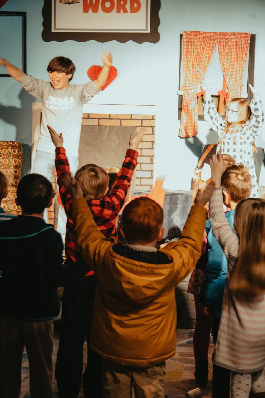 Children with their hands up during a song.