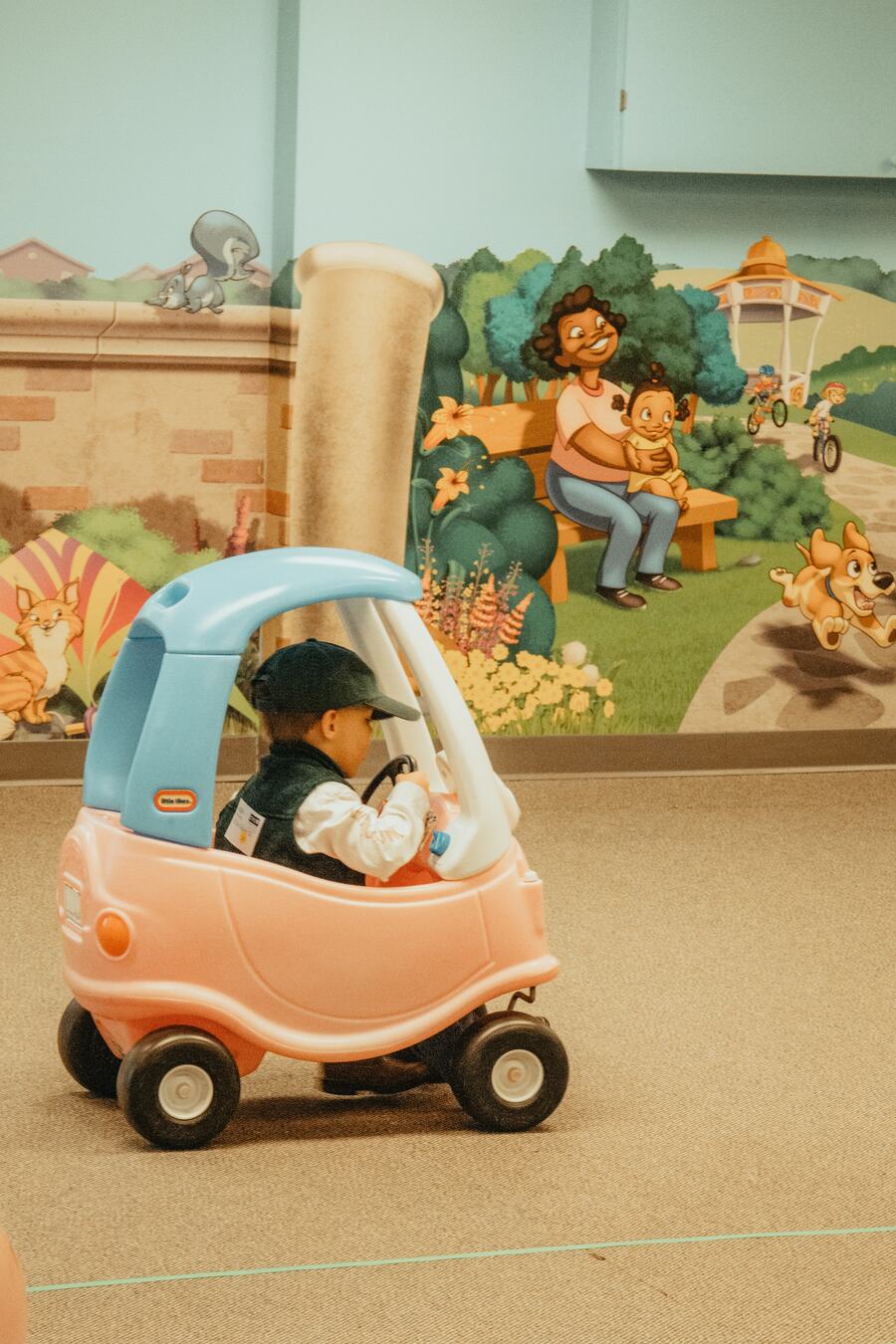 A child in a toy car in the hallway.