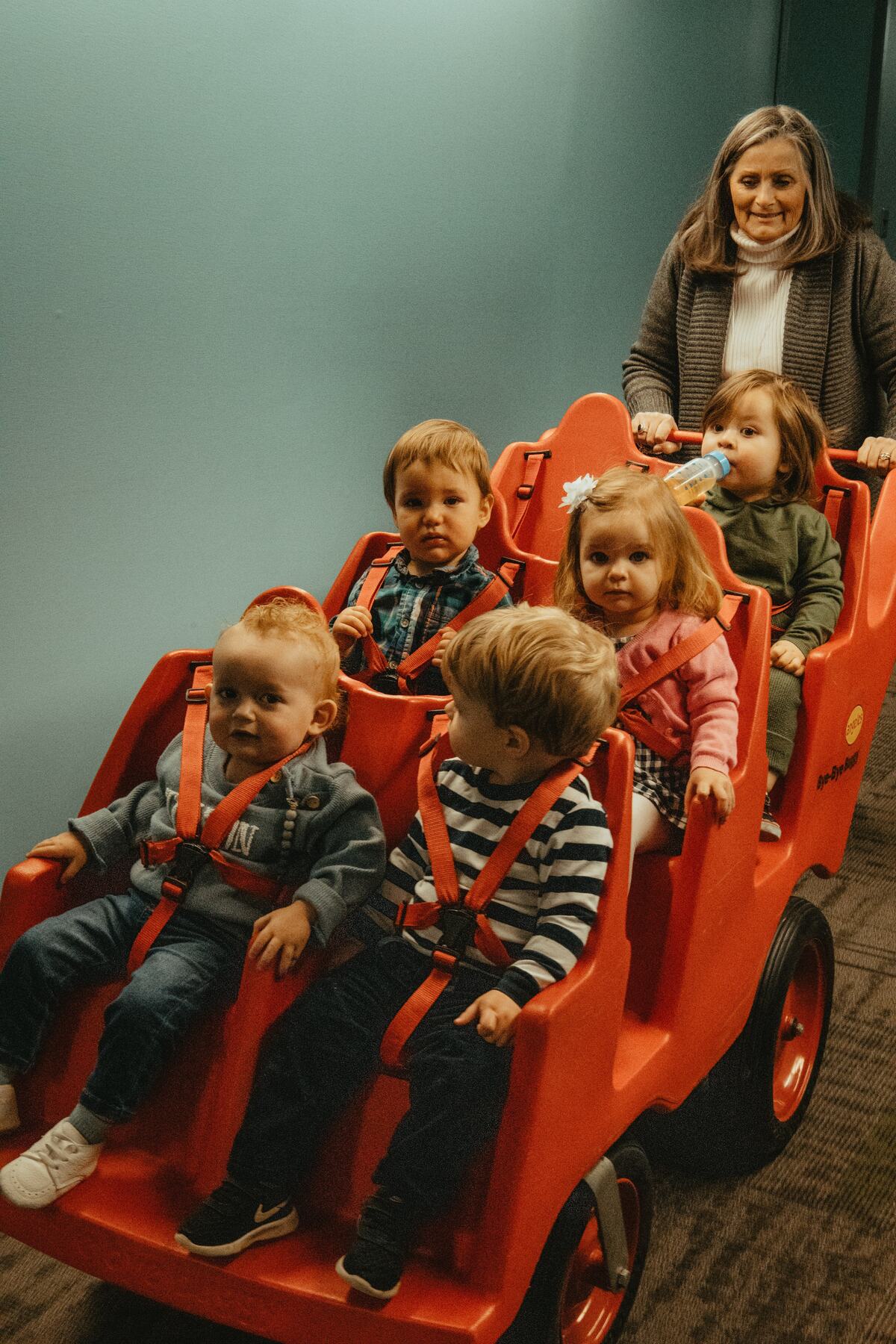 A leader pushing a wagon full of toddlers.
