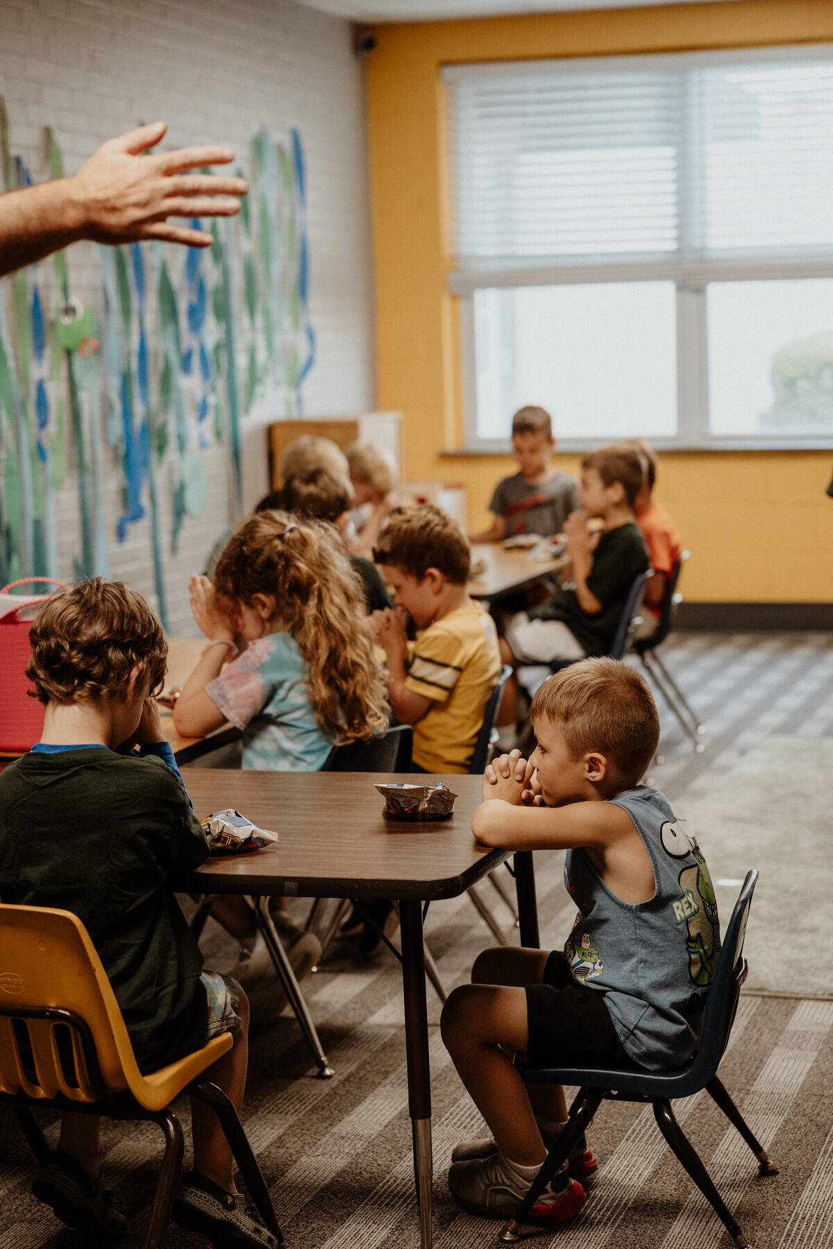A classroom of children at the tables.