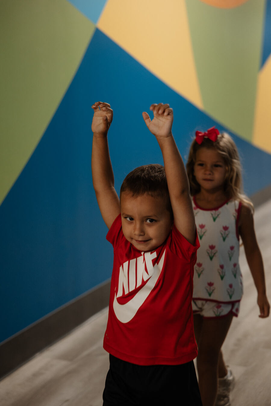 Two children with their hands up by the painted wall.