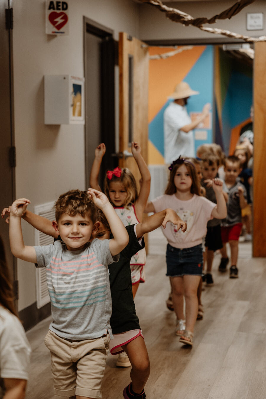 Children running down the hallway with their hands up.