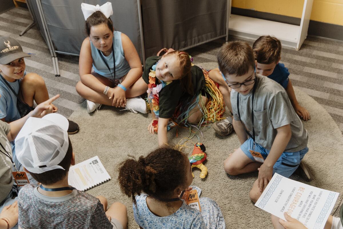 Children working through their sheets on the floor.