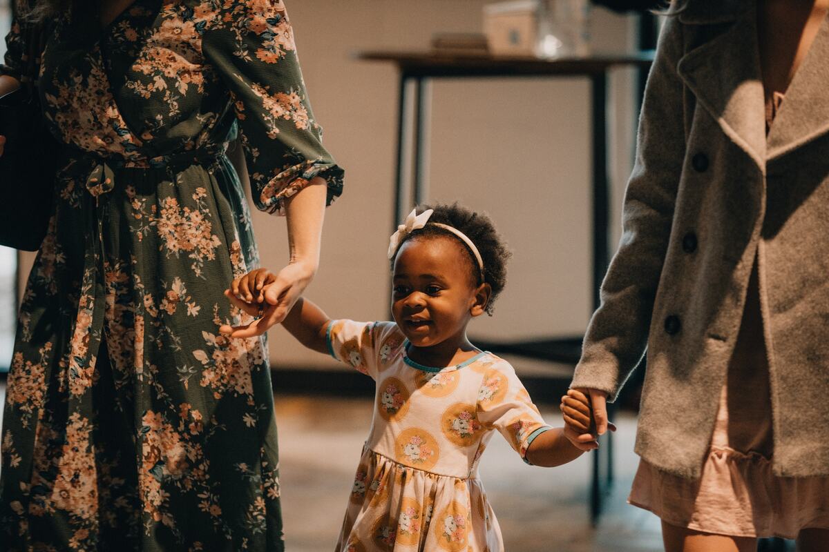 A young child walking in with a parent.