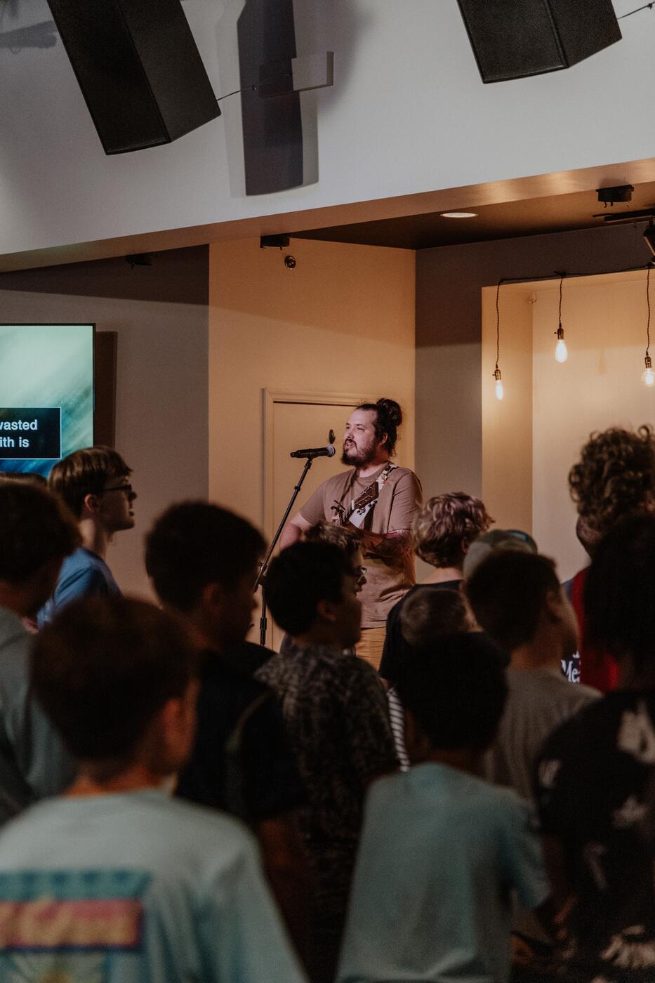 Students standing for worship as the band plays.