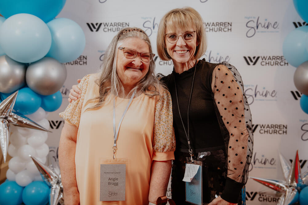 A guest and a volunteer at the backdrop.