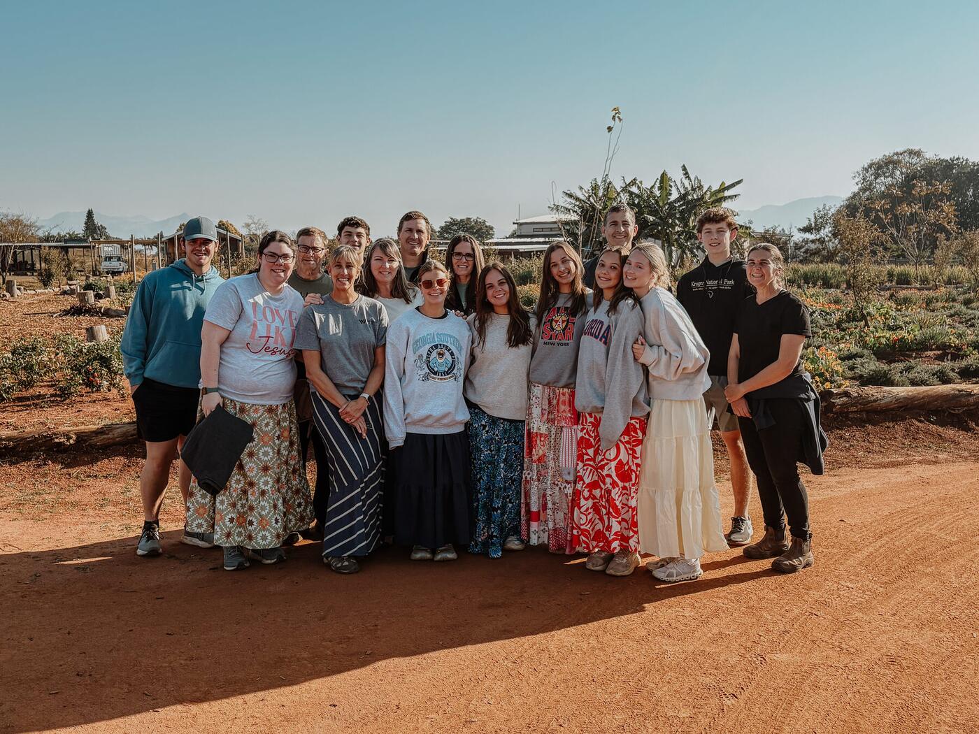 A mission team standing together on a red dirt road.