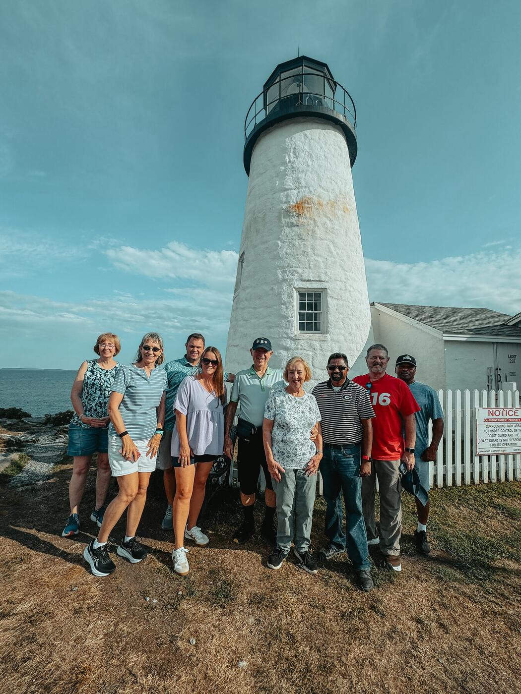 A team gathered at the foot of a lighthouse.