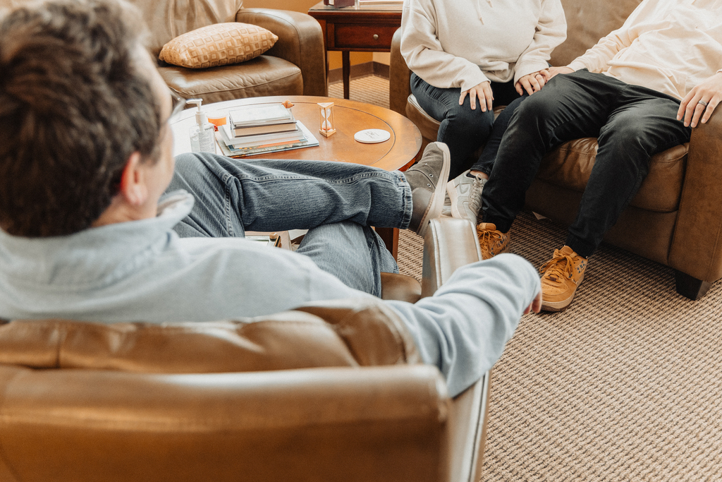 A couple sitting with a counselor around a low table.