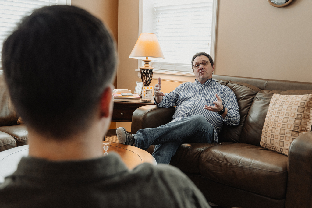 A counselor talking with someone in a sitting room.
