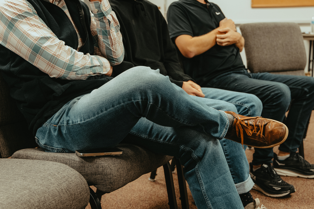 People seated in a row of chairs at a group meeting.