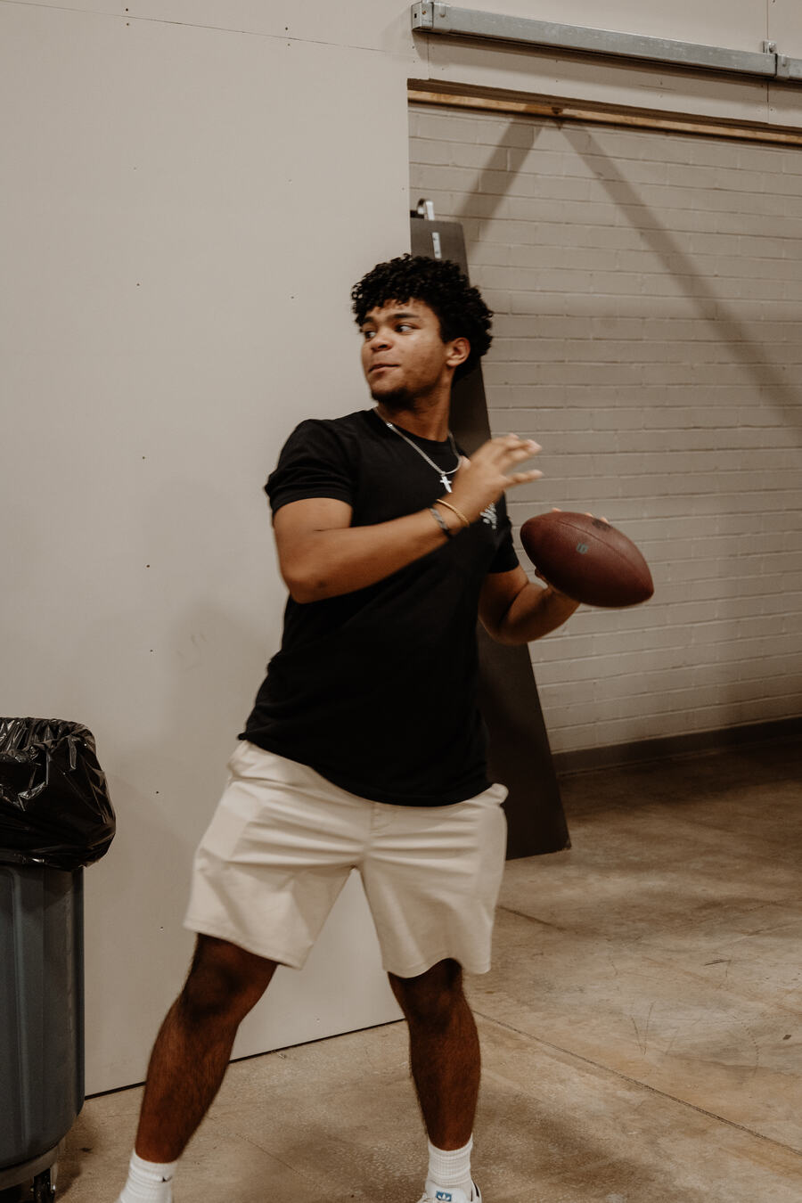 A student throwing a football indoors.