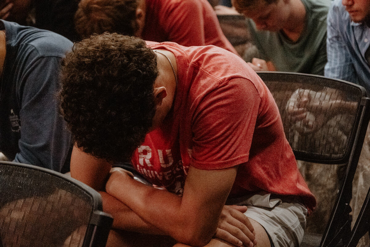 A leader praying with a student.