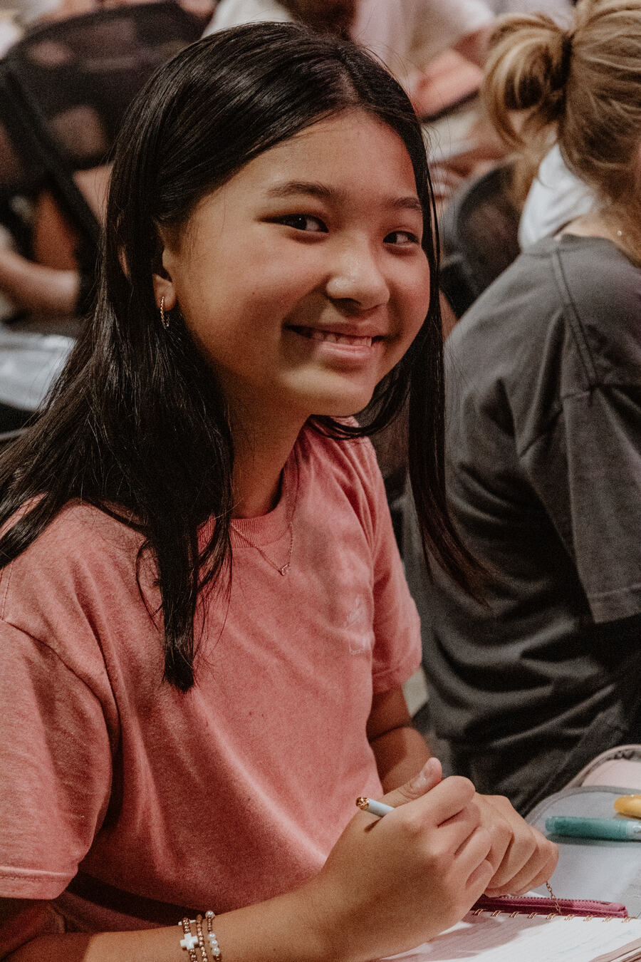 A student smiling, notebook open in her lap.