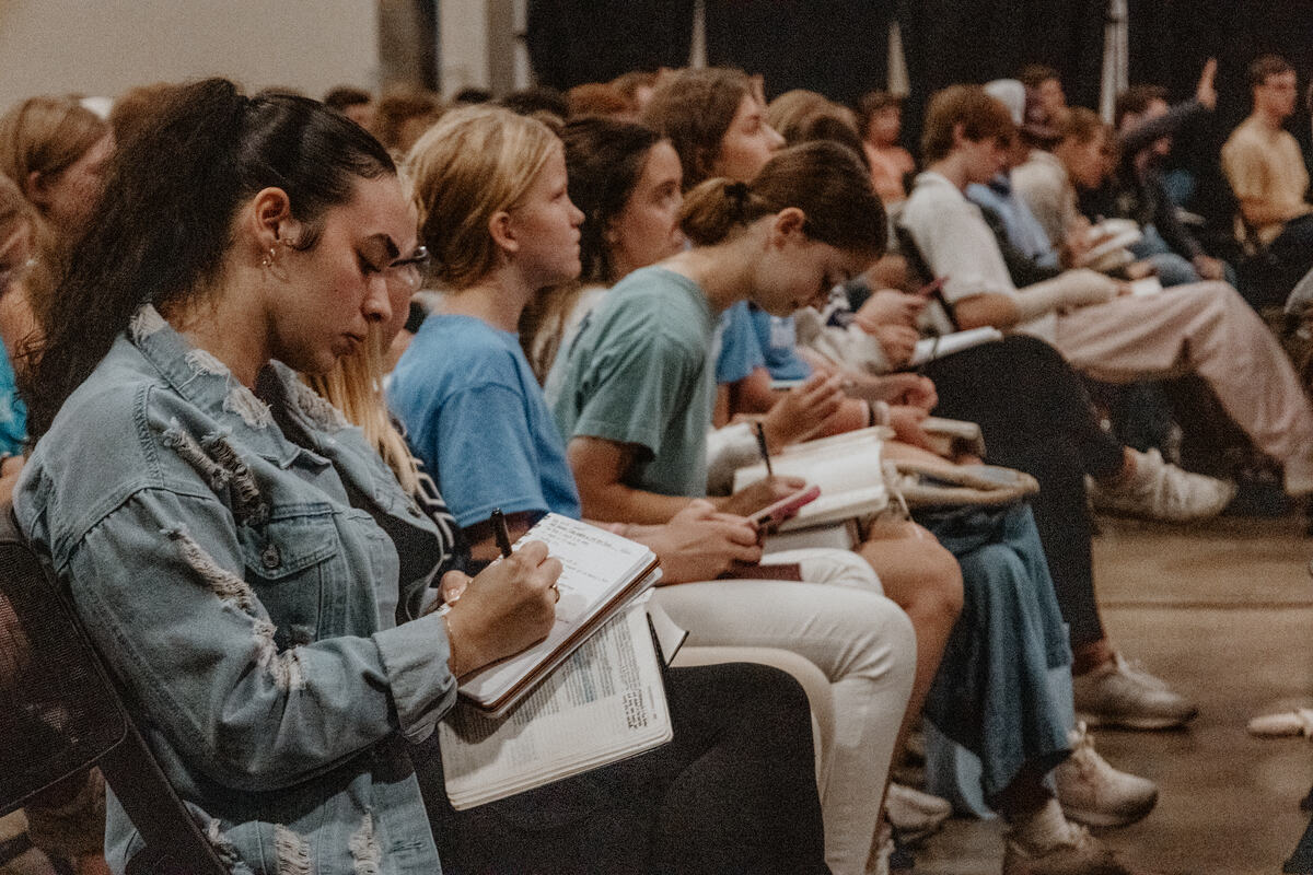 A row of students writing in their notebooks.