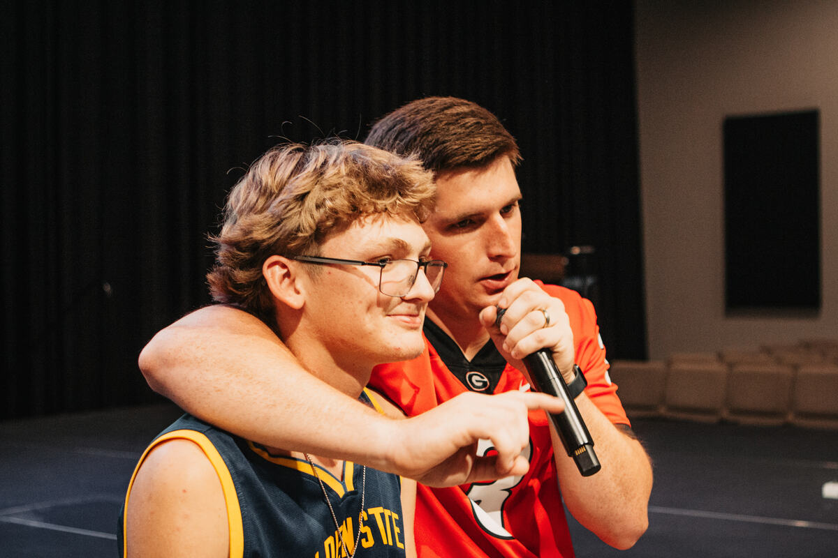 A leader with a microphone beside a student.