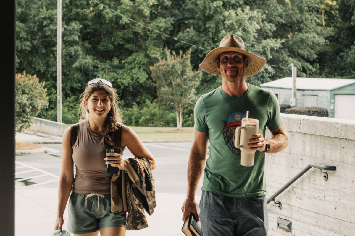 Two students walking outside with drinks.