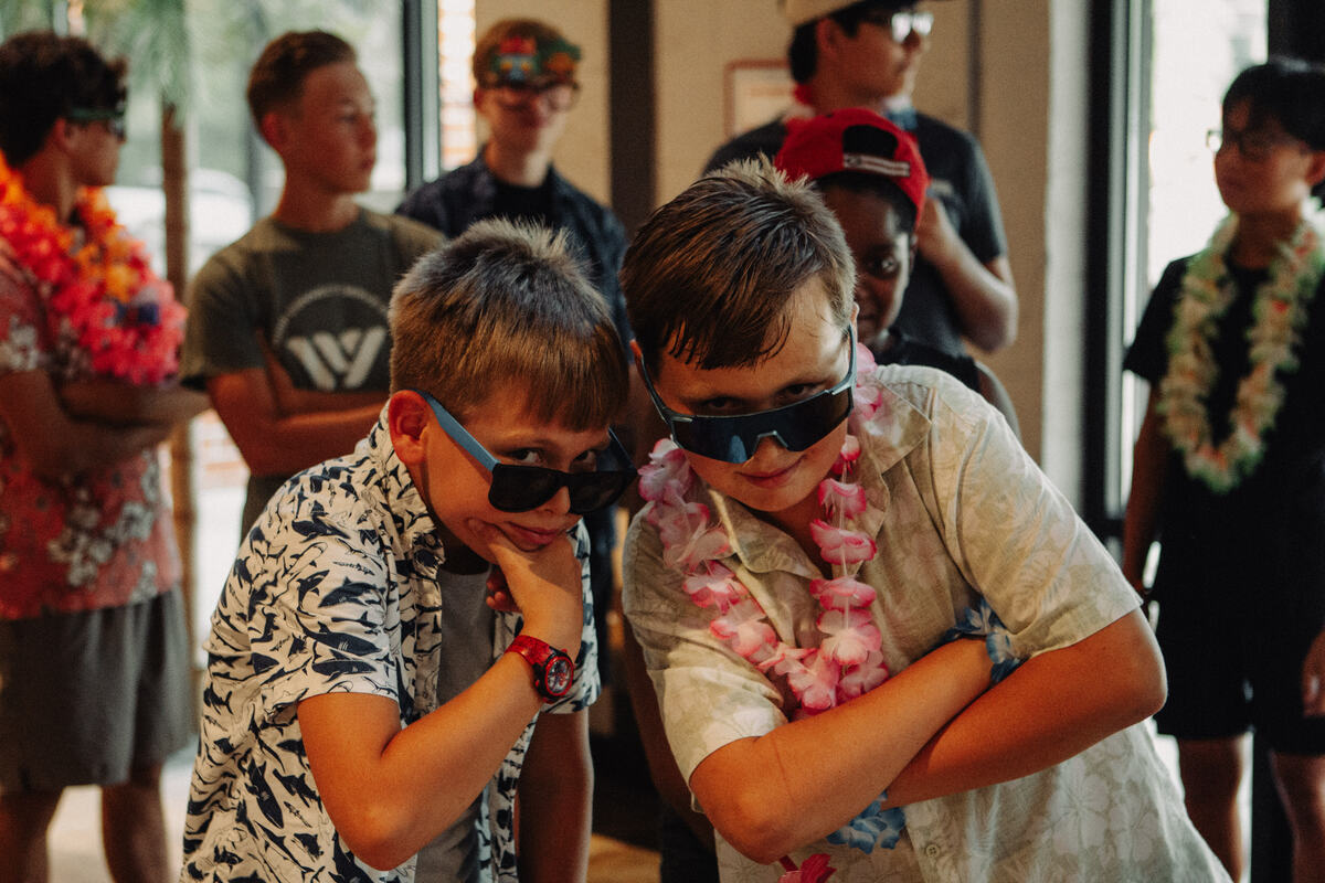 Two students laughing in sunglasses and leis.